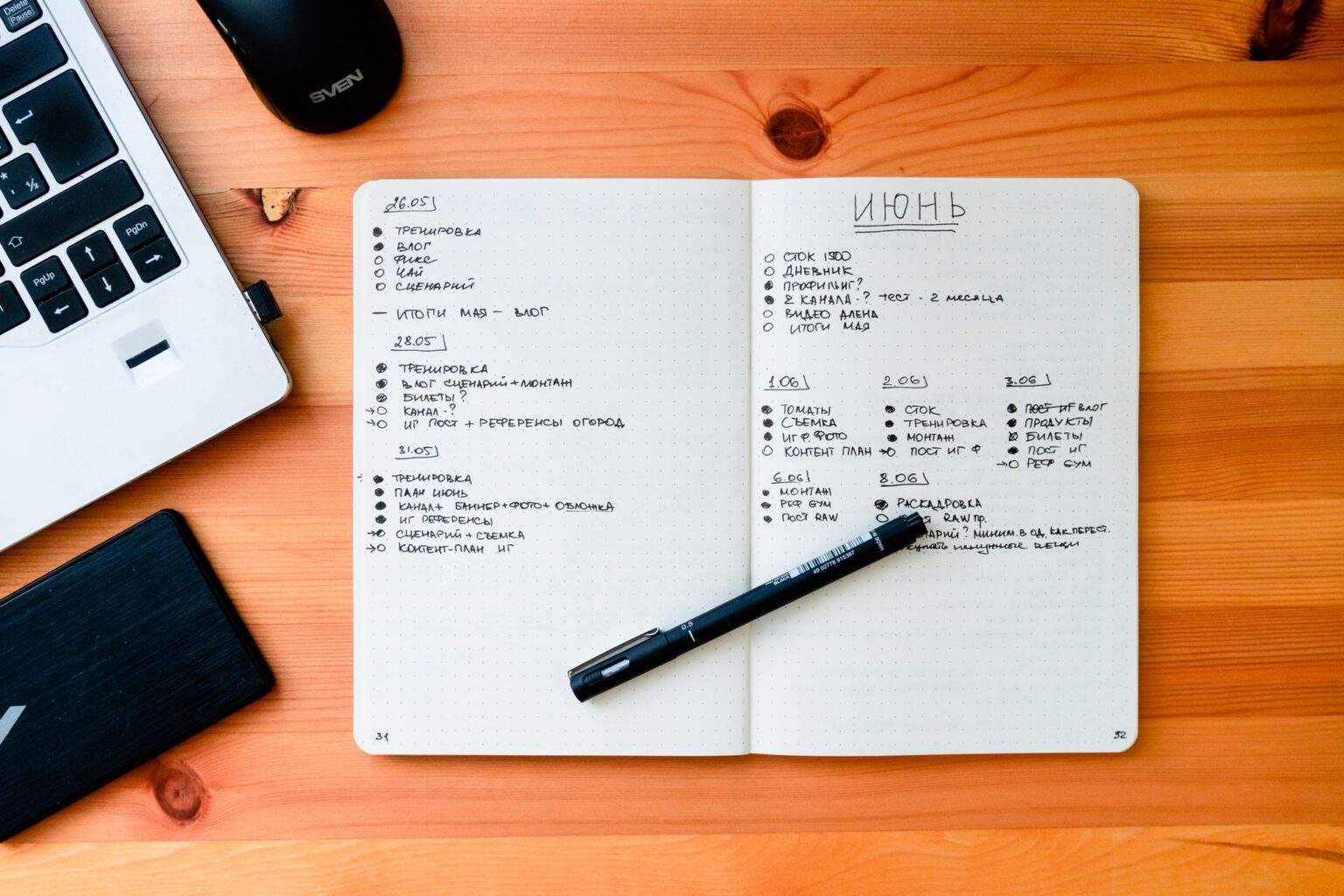 Open notebook with handwritten notes next to a laptop on a wooden desk